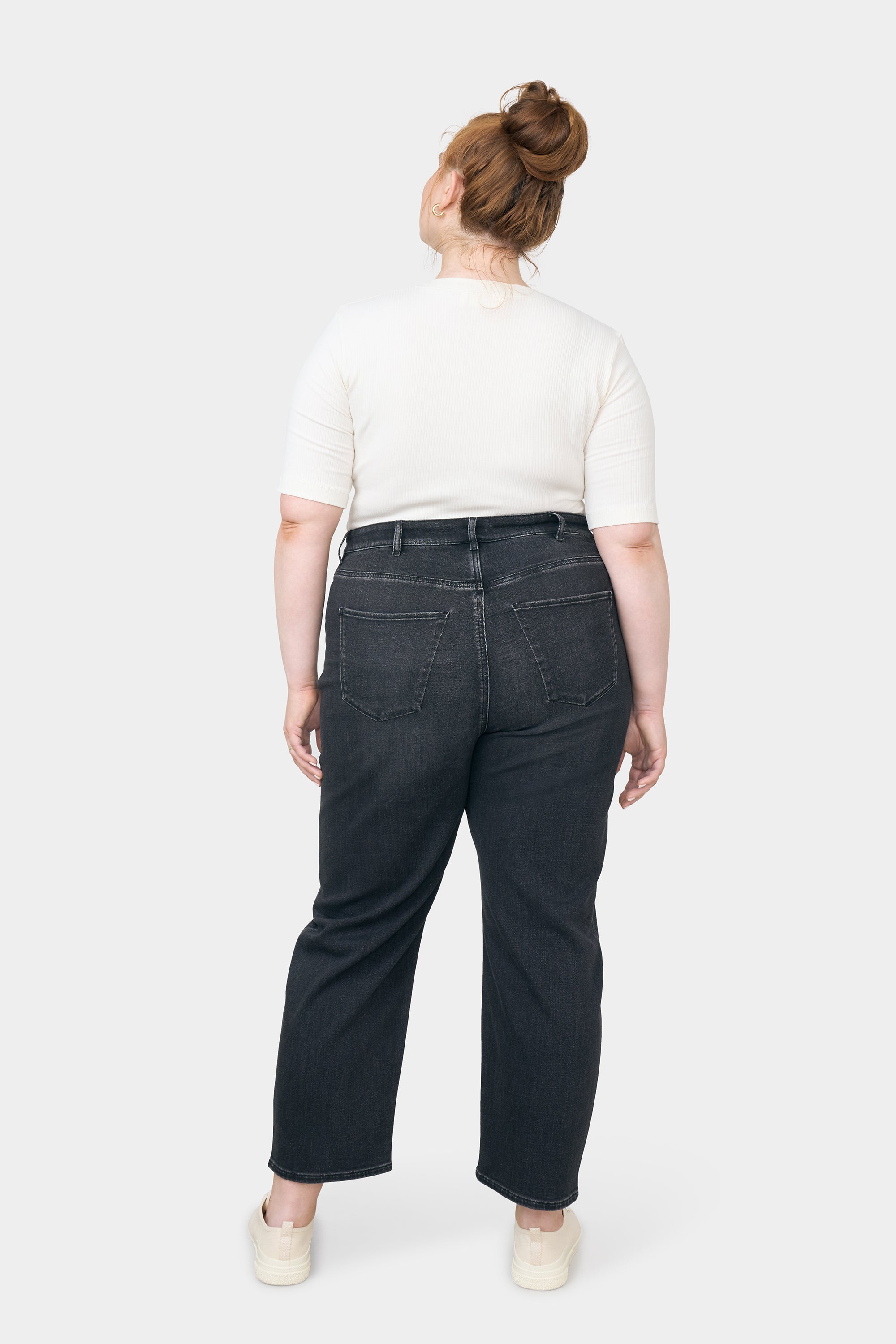 Rückansicht einer Frau in dunkler STARDUST O-Shape Jeans mit hohem Bund, entspannter Hüfte und zum Saum verengtem Bein; zwei Gesäßtaschen sichtbar.