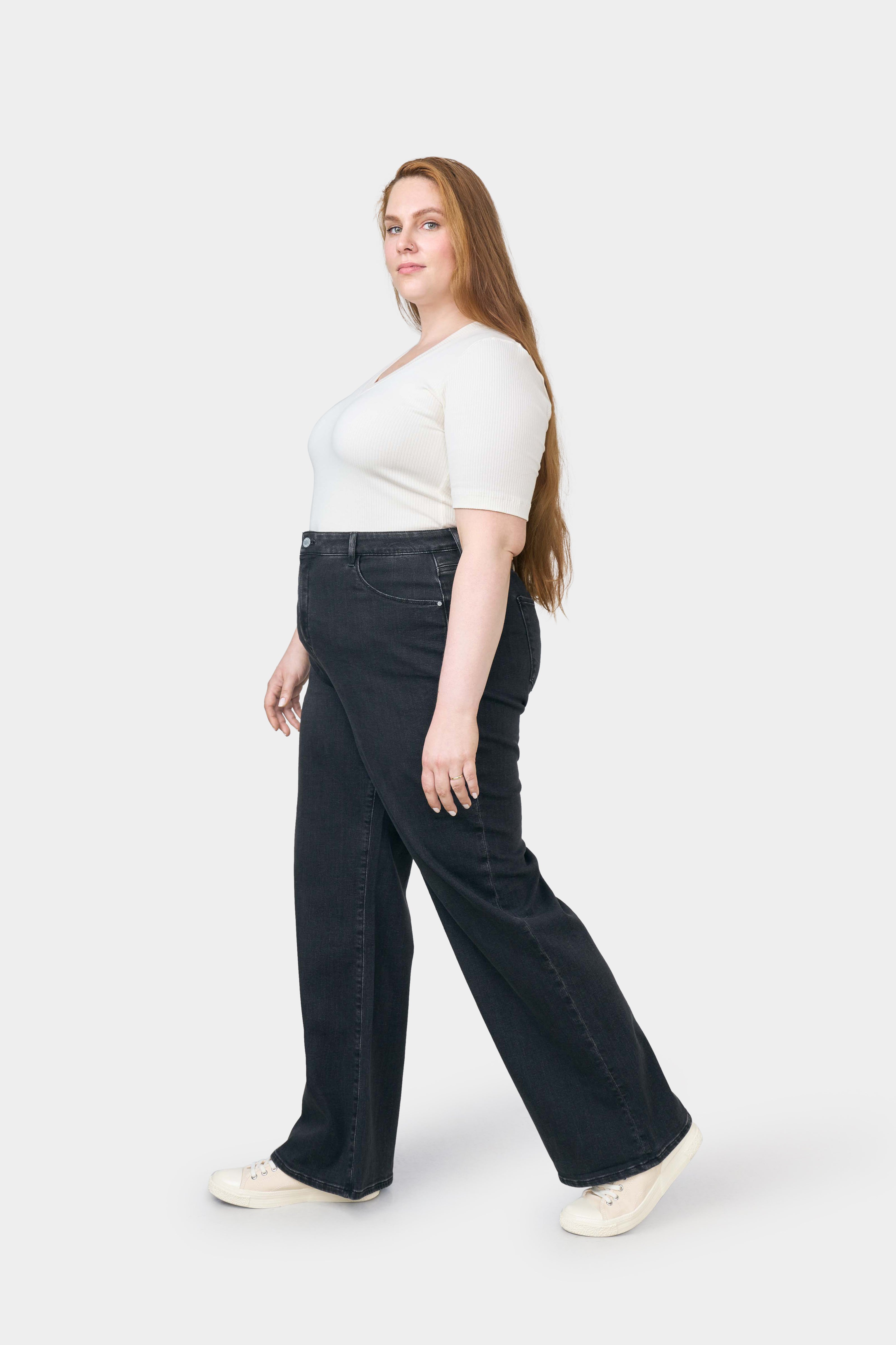 Dunkle DEW Flared Soft Denim Jeans – Classic/Curvy, High-Waist, ausgestelltes Bein, Seitenansicht eines Models mit weißem Oberteil.