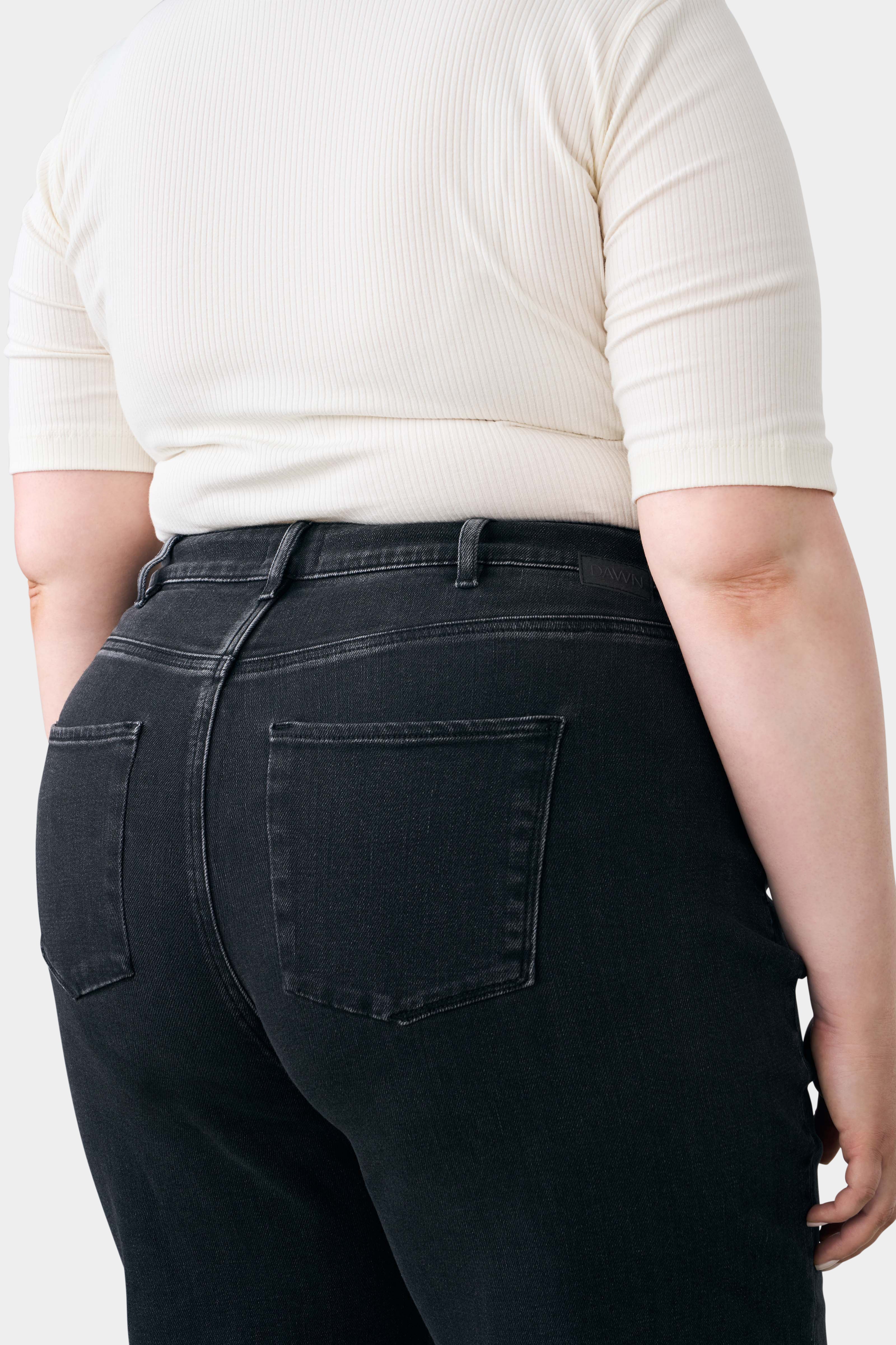 Rückansicht einer schwarzen DEW Flared Soft Denim Jeans in High Waist von DAWN, mit zwei Gesäßtaschen und Gürtelschlaufen.
