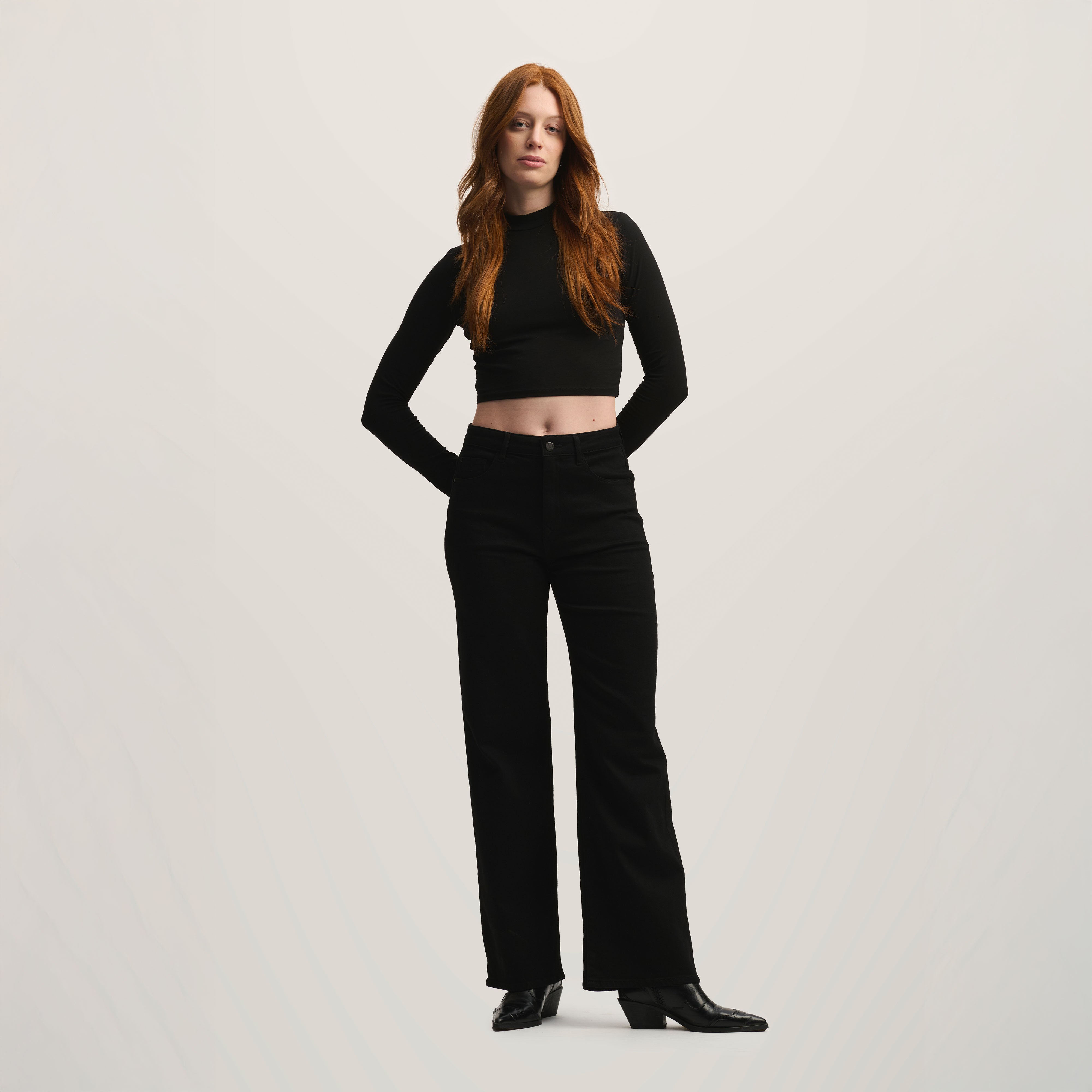 Schwarze DEW Flared Jeans Classic mit hohem Bund und ausgestelltem Bein in Stay Black; Five-Pocket-Design, am Model getragen.