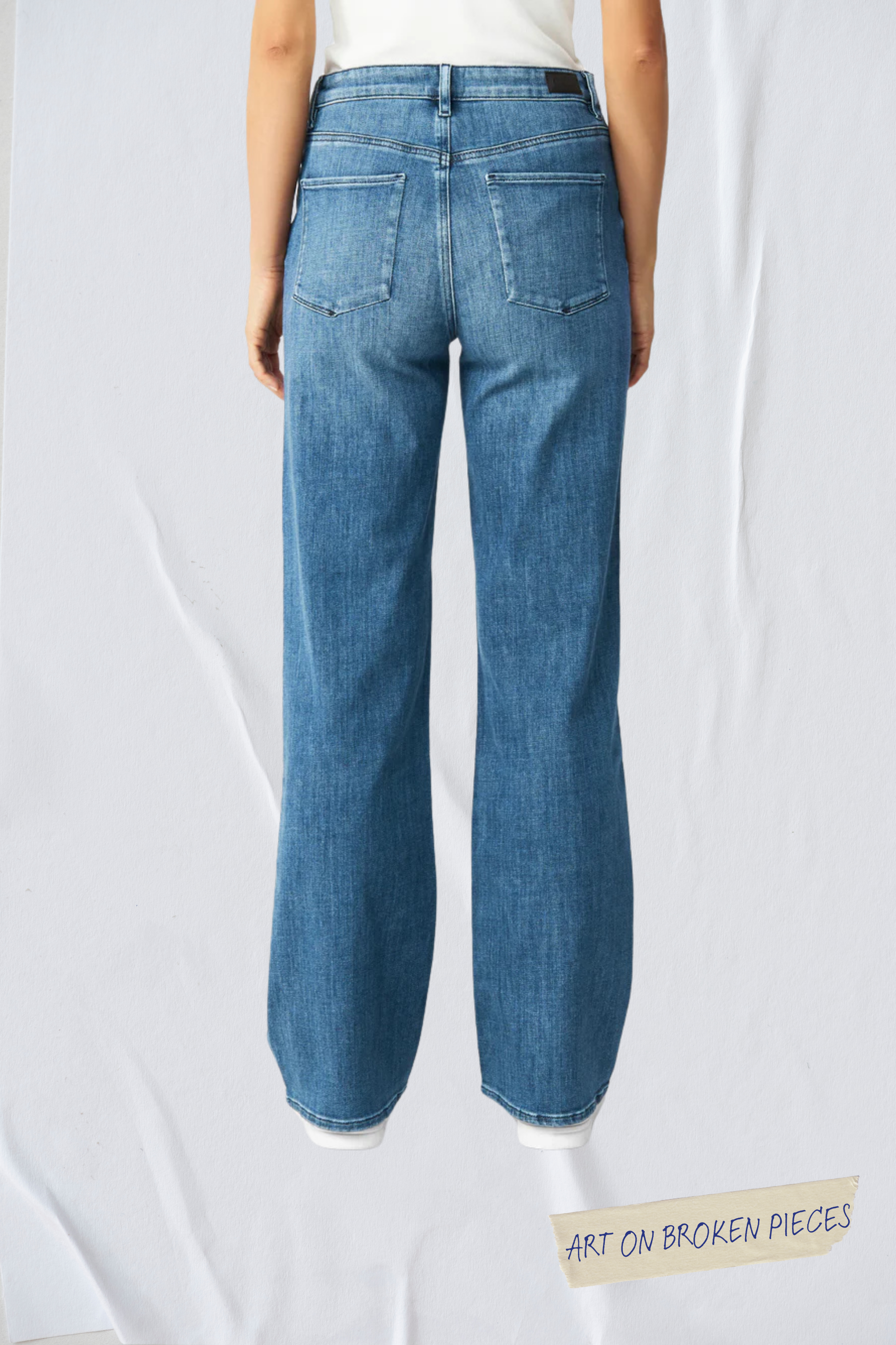 Rückansicht der DEW Classic Flared Jeans in Blau, hoher Bund, ausgestelltes Bein, zwei Taschen – Art on Broken Pieces Edition.
