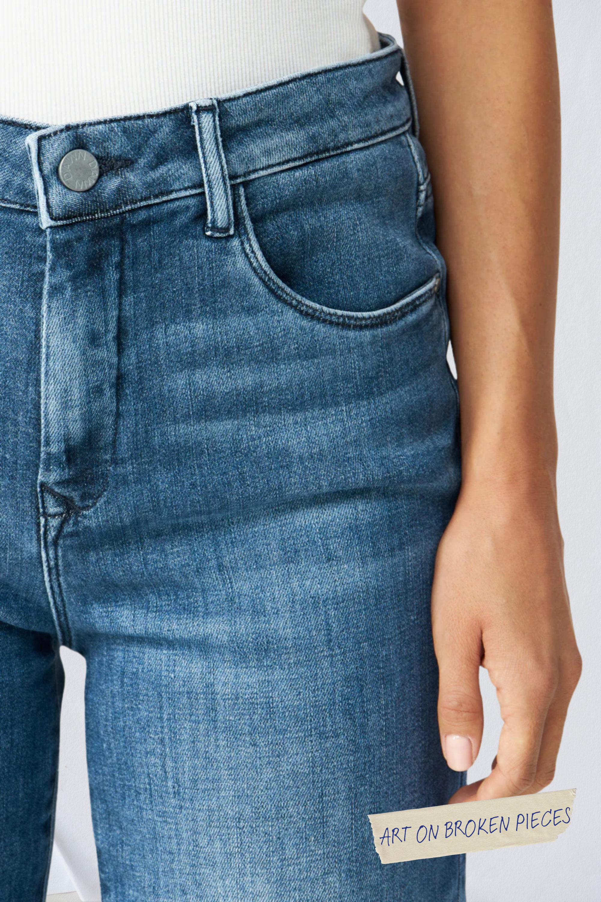 DEW Classic High-Waisted Flared Jeans, Blue; am Oberschenkel klebt ein Aufkleber 'ART ON BROKEN PIECES'.