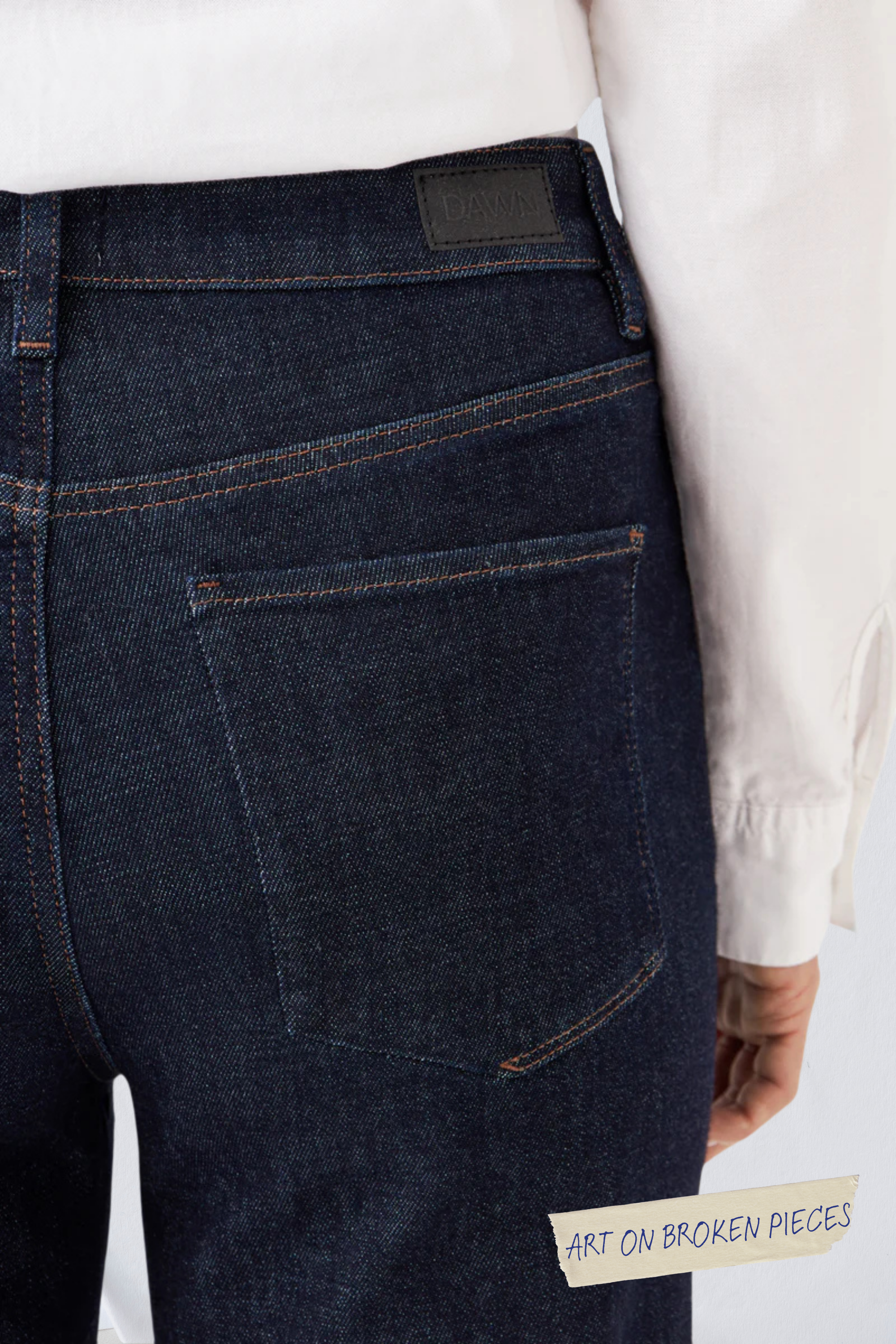 DEW Classic Flared Jeans in Raw Blue, hohe Taille, ausgestelltes Bein, Rückentaschen; DAWN-Label am Bund und Sticker 'Art on Broken Pieces' sichtbar.