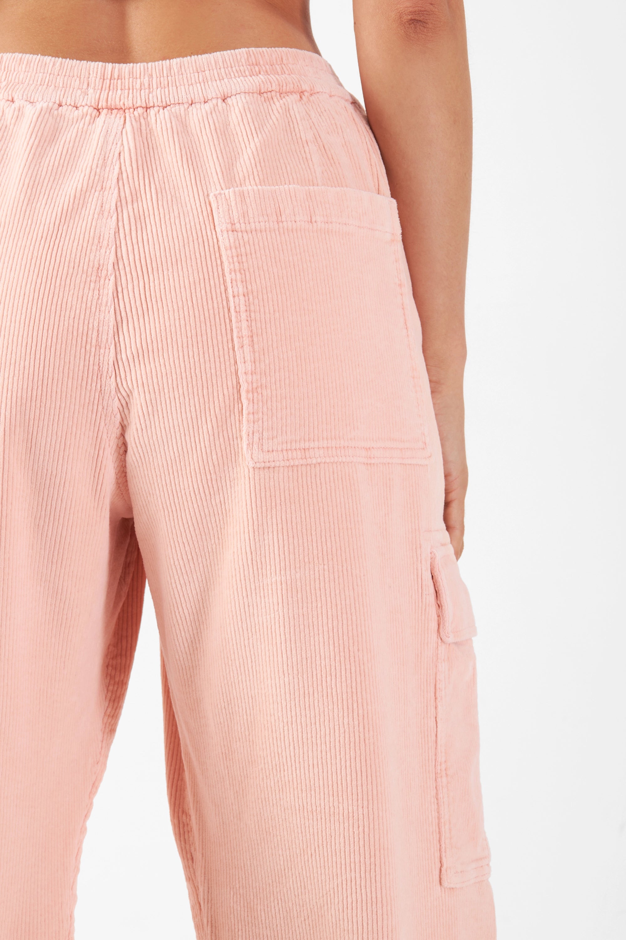 Rosa Corduroy-Hose mit mittlerer Taille, elastischem Bund und Cargo-Taschen am Oberschenkel – Nahaufnahme des weichen Cord-Stoffs.