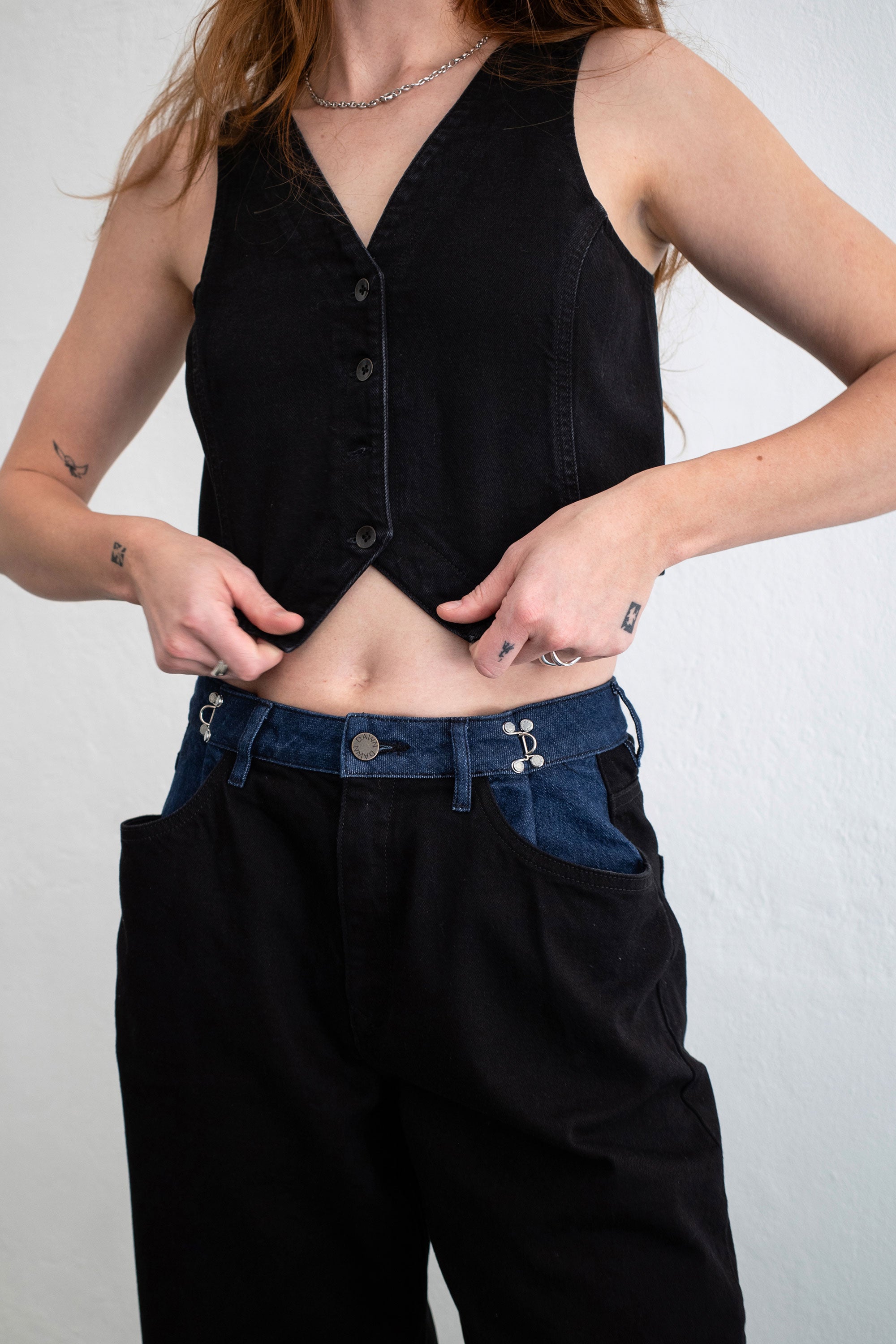Dunkelblaue Denim-Weste mit V-Ausschnitt und Knopfleiste, tailliert – Frontansicht einer Person.