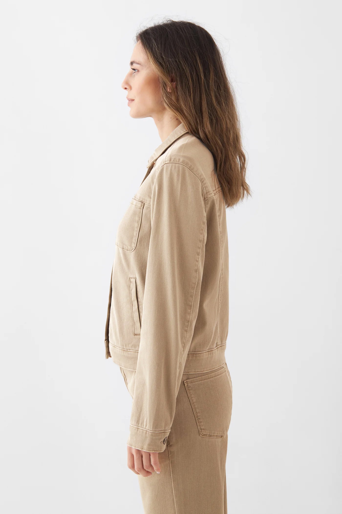 Seitliche Ansicht einer Frau in der CALLISTO Jacke Soft Organic in Warm Sand – klassische Jeansjacke mit Brusttaschen.