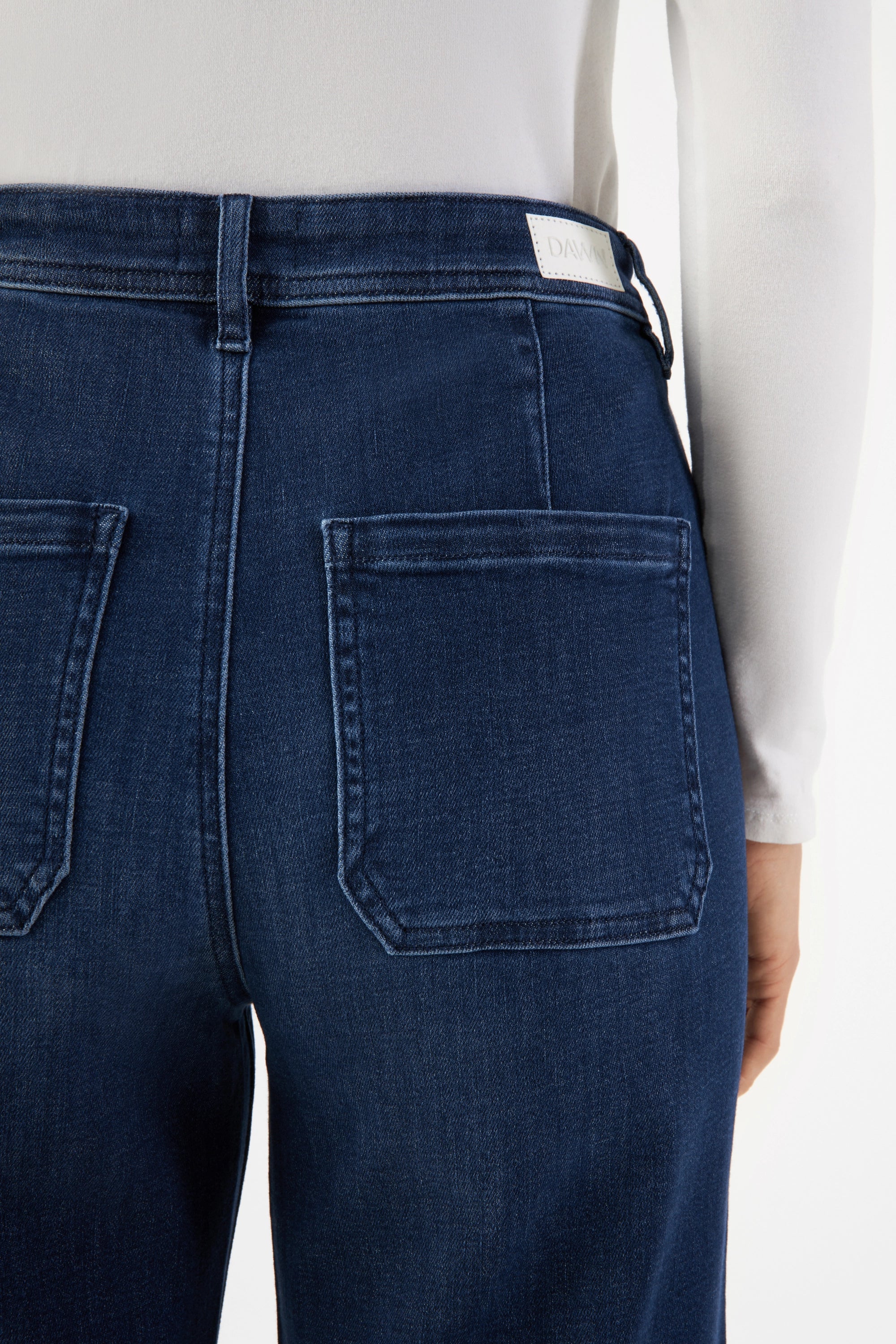 Rückansicht einer dunkelblauen DEW Sailor High-Waist Jeans mit zwei aufgesetzten Gesäßtaschen; Markenlabel am Bund sichtbar.