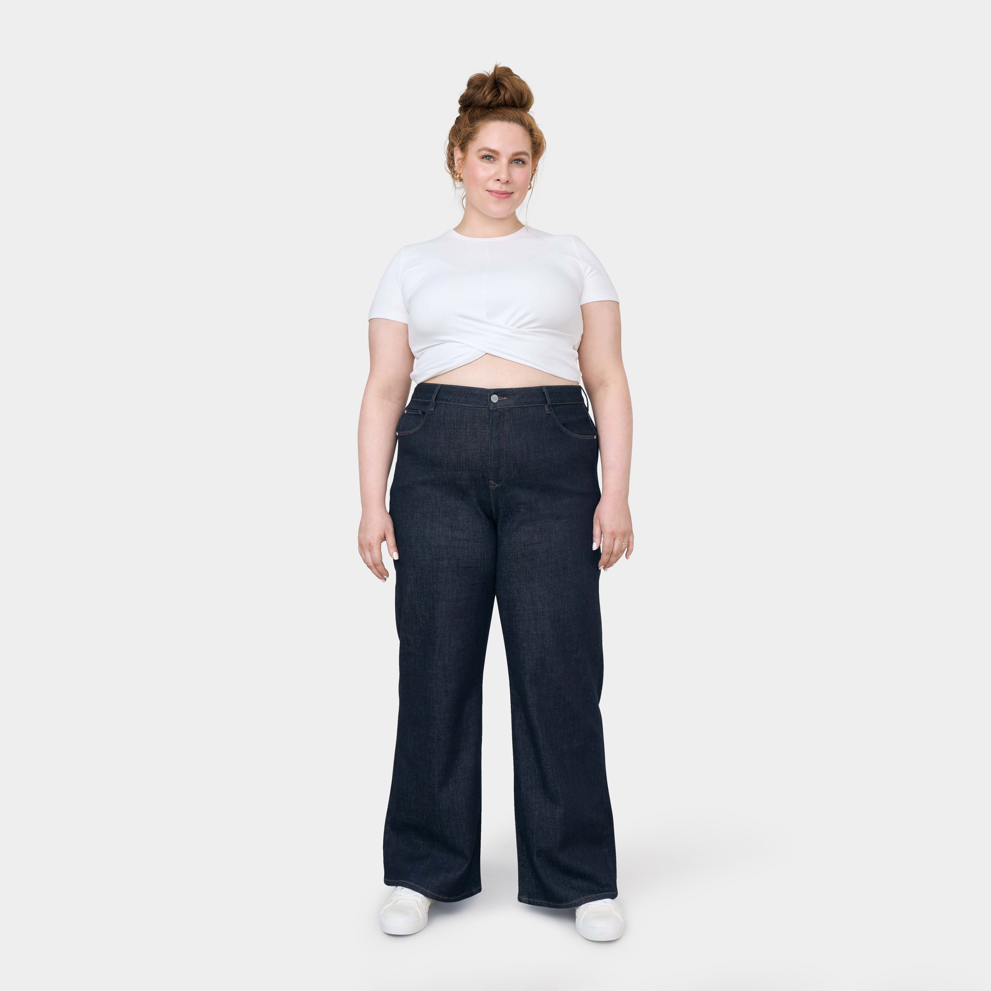 DEW Flared Soft Denim in Raw Blue – High-Waist, ausgestelltes Bein, klassisches Five-Pocket-Design mit Stretch; getragen von einer Frau in weißem Top.