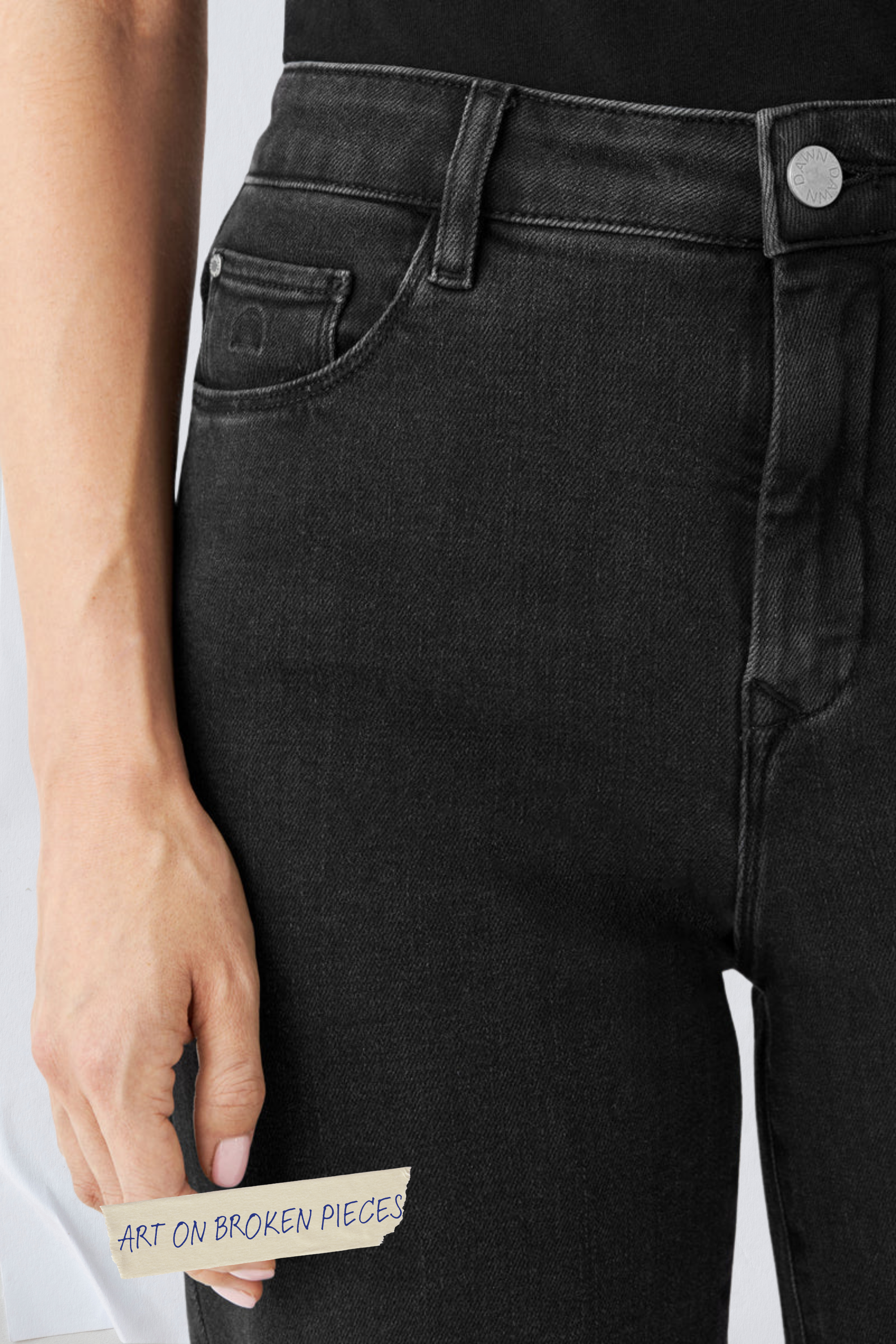 Schwarze DEW Classic Flared Jeans, High Waist, ausgestelltes Bein; 'ART ON BROKEN PIECES' Aufkleber am Hosenbein.
