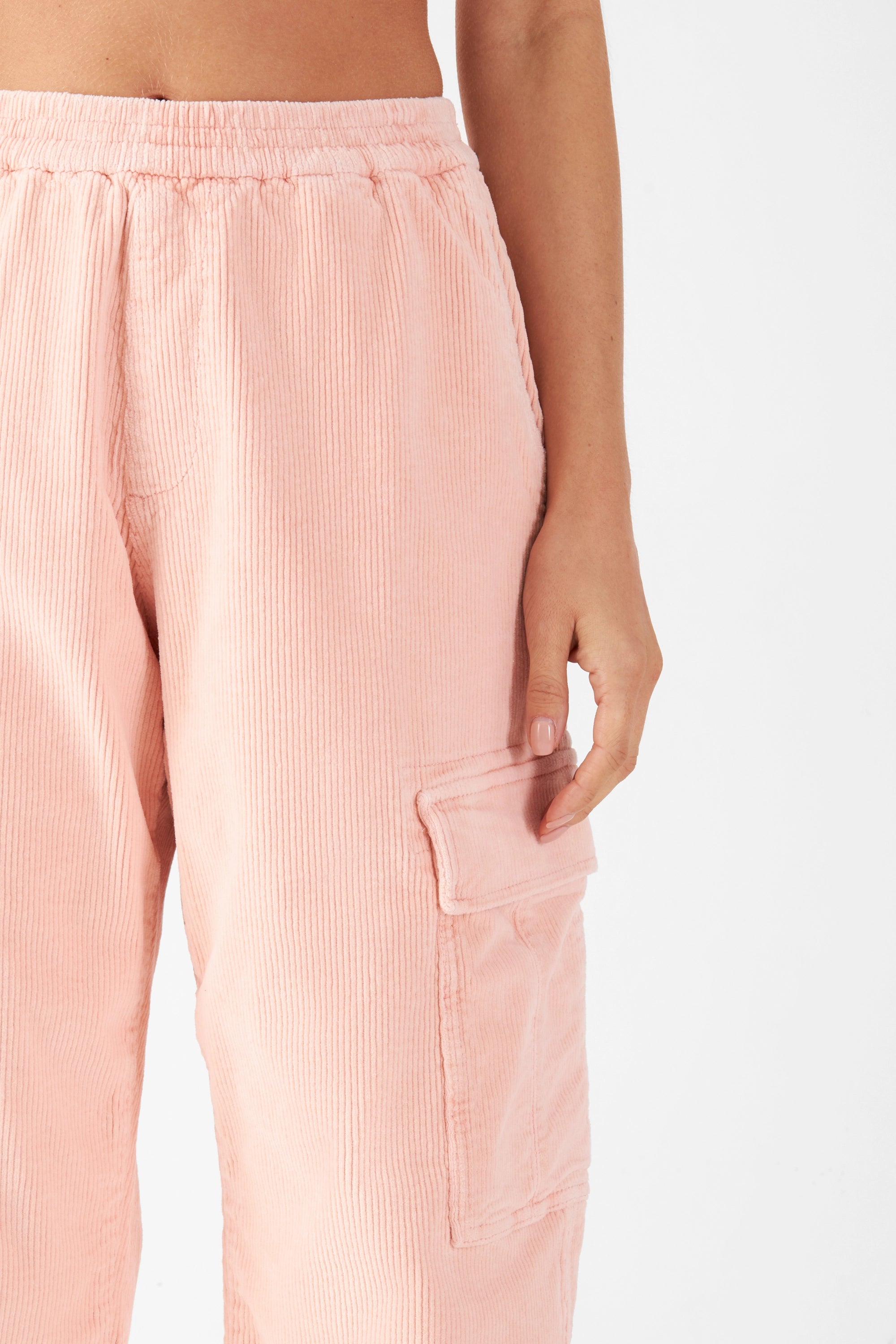 Rosafarbene Cordhose mit mittlerer Taille, lockerer Passform und elastischem Bund; seitliche Cargo-Tasche mit Klappe sichtbar – Nahaufnahme der Hüft-/Beinseite.