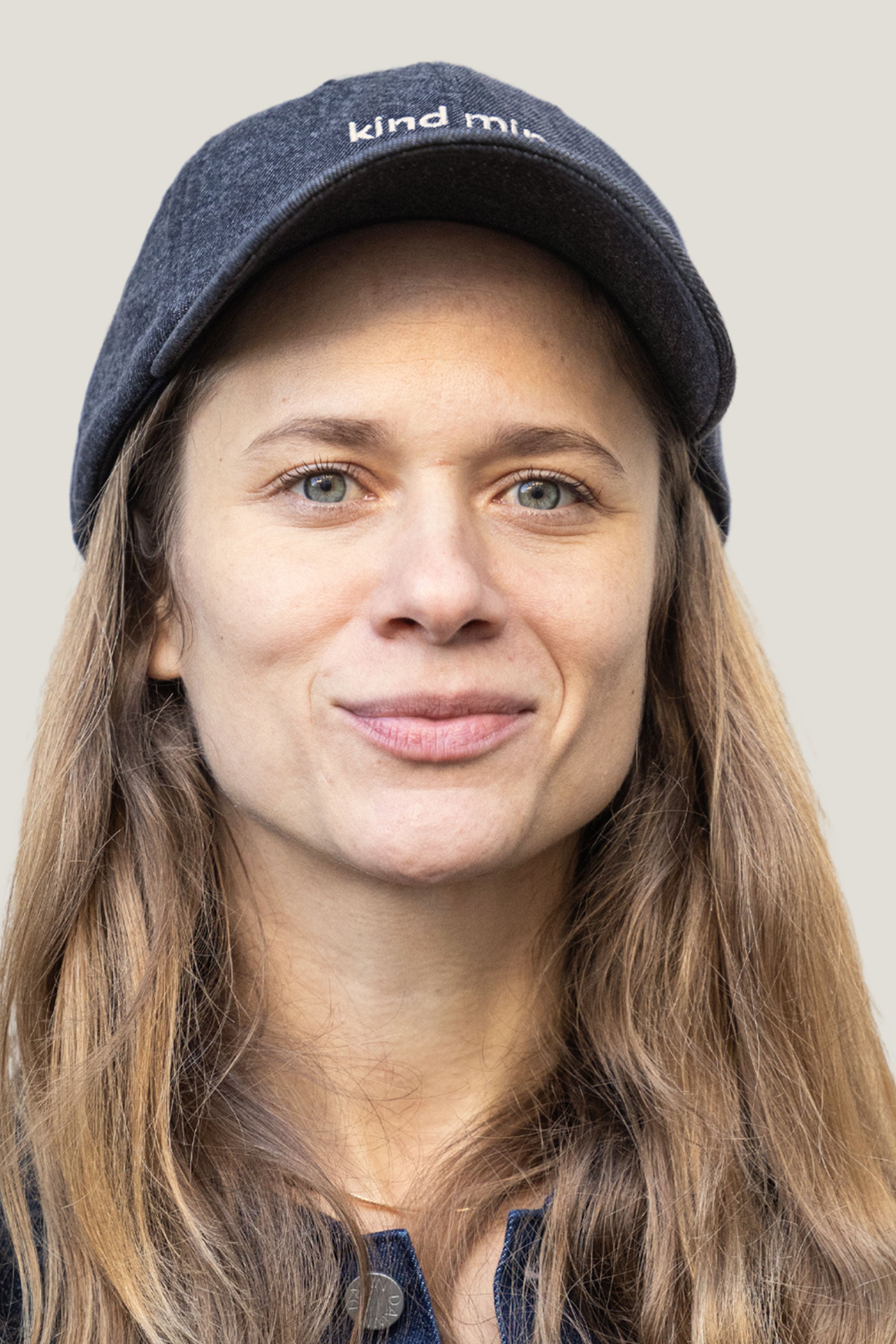 Nahaufnahme einer Person mit dunkelgrauer Denim-Cap 'kind mind' vorne mit Logo; Cap aus Bio-Baumwolle, limitierte Auflage.